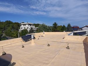 A képen lapostető szigetelés purhabbal kivitelezése látható, ahol a szórt purhab hézagmentes, vízzáró és hőszigetelő réteget képez.